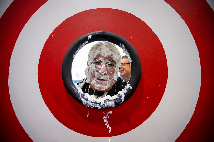 Tim Dove, president and chief executive officer, looks out from the middle of a target after getting a pie in the face during Pioneer Fair at Pioneer Natural Resources